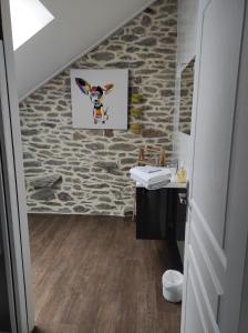 a bathroom with a sink and a stone wall at La Petite Roupie in Bretteville