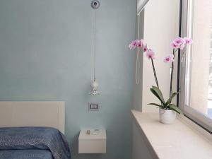 een slaapkamer met een bed en een vaas met roze bloemen bij RosAmar in Bari