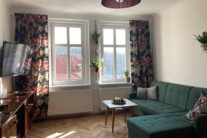 克沃茲科的住宿－Apartament Stara Kamienica 1930r.，客厅设有绿色沙发和2扇窗户。