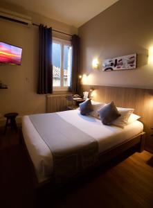 - une chambre avec un grand lit blanc et une fenêtre dans l'établissement Le Strasbourg Hotel, à Montpellier