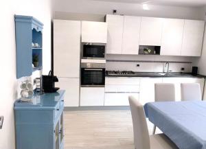 una cocina con armarios blancos y una mesa azul en B&B La coccola, en Lainate