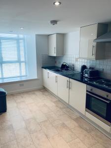 a kitchen with white cabinets and a tile floor at Cliffview Apartment in Arbroath