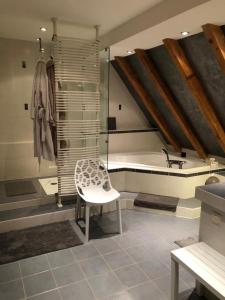 a bathroom with a tub and a chair and a sink at La maison rouge in Ostheim