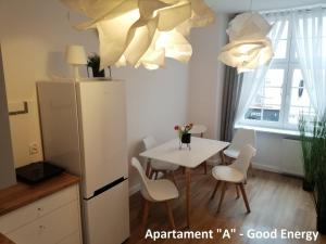 a kitchen with a white refrigerator and a table with chairs at Apartament Elbląg GoodEnergy - Stare Miasto, Oldtown, Altstadt in Elblag