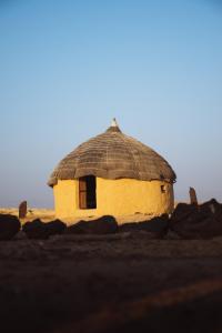 a hut with a thatched roof in the desert at Room Factory Hotels Chhatrel in Jaisalmer