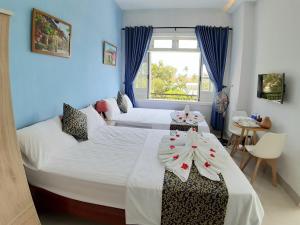 Duas camas num quarto com paredes azuis e uma janela em Ngoc Diep Homestay Hoi An em Hoi An