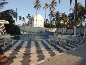 un complejo con una piscina con sillas blancas y palmeras en Phuong Tay Guest House, en Mui Ne
