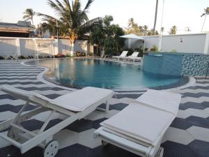 una piscina con 2 sillas blancas al lado en Phuong Tay Guest House, en Mui Ne
