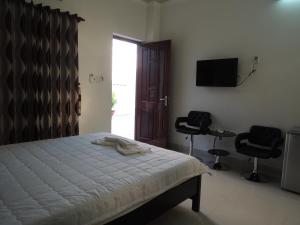 1 dormitorio con 1 cama, 2 sillas y TV en Phuong Tay Guest House, en Mui Ne