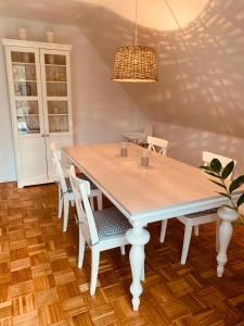 a dining room table with white chairs and a chandelier at mitten im dorf in Worpswede