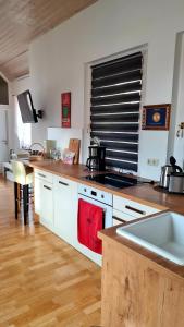a kitchen with white cabinets and a wooden floor at Apartement *Harzblick* in Nordhausen