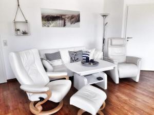 a living room with white furniture and a table and chairs at Ferienwohnung Wellenreiter in Sassnitz