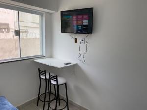 a room with two bar stools and a tv on the wall at Pedra Branca in Campinas