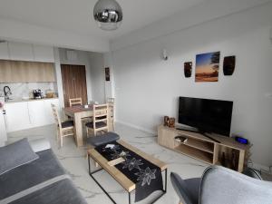 a living room with a couch and a tv and a table at Apartament Kapitana Sea Wave in Darłówko