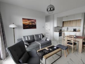 a living room with a couch and a table and a kitchen at Apartament Kapitana Sea Wave in Darłówko