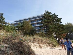 a group of people walking on the beach in front of a building at Apartament Kapitana Sea Wave in Darłówko