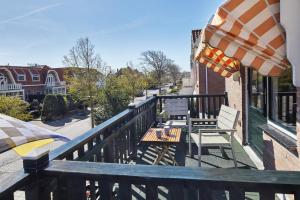 a balcony with a table and chairs and an umbrella at Guest House Aquarius in Zandvoort