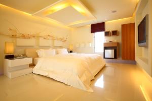 ein Schlafzimmer mit einem großen weißen Bett und einem TV in der Unterkunft Elan-Motel in Wujie