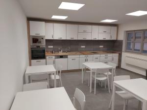 a kitchen with white cabinets and white tables and chairs at Fűzfa Vendégház in Bogács