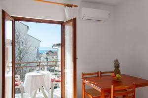 uma sala de jantar com uma mesa e uma varanda em Niko Apartments em Drvenik