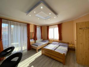 1 dormitorio con 2 camas, sillas y ventana en Millennium Lux Apartments en Hajdúszoboszló