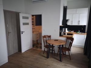 eine Küche mit einem Tisch und Stühlen sowie eine Küche mit weißen Schränken in der Unterkunft Solaris Apartments Self-Check-In in Oppeln