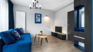 een woonkamer met een blauwe bank en een tafel bij Comfy Apartments - Park Technologiczny in Gdynia