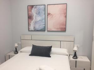 sypialnia z białym łóżkiem z 3 obrazami na ścianie w obiekcie Apartamentos La Encarnación III w mieście Los Alcázares