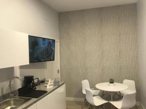 TV y cocina con mesa y sillas blancas. en Apartamentos La Encarnación III en Los Alcázares