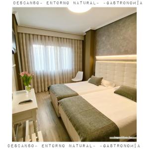 a hotel room with two beds and a desk at Hotel Rural Peñalabra in Cervera de Pisuerga