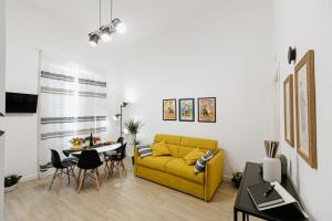 ein Wohnzimmer mit einem gelben Sofa und einem Tisch in der Unterkunft Les Amis in Syrakus