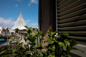 Blick auf eine Kirche aus einem Fenster mit einer Pflanze in der Unterkunft Les Amis in Syrakus