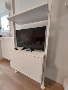 a white dresser with a tv on top of it at Au Jardin de la Saudrune in Villeneuve-Tolosane