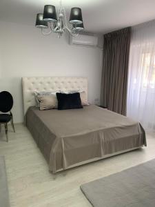 a bedroom with a large bed and a chandelier at Leon Apartment in Brăila