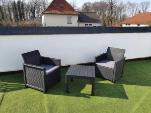 パイネにあるEdemissener Gästezimmerの柵の横の芝生の上に椅子2脚とテーブル