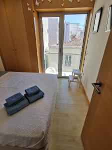 two towels on a bed in a room with a large window at Casa Picadeiro in Figueira da Foz