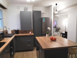 una cocina con armarios negros y un bol de fruta en una mesa en Appartement tout confort 2 chbres - 72m2 - avec terrasse et vue Pyrénées, en Pau