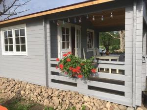 a small house with a porch with a bench and flowers at Dižozoli in Priekule