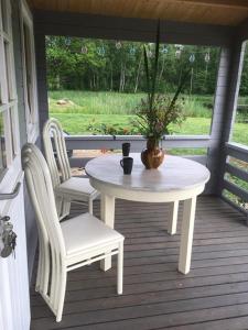 een tafel en stoelen op een veranda met een vaas erop bij Dižozoli in Priekule