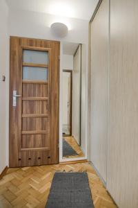 コニンにあるWłasne M - Studioの木製のドアと敷物が敷かれた空の廊下