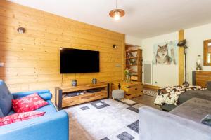 een woonkamer met een houten muur en een flatscreen-tv bij Le Reclard - Les Balcons Etoilés in Champagny-en-Vanoise