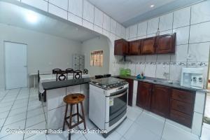 a kitchen with wooden cabinets and a stove top oven at Hostel Lençóis Park in Barreirinhas