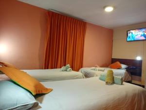 a hotel room with two beds and a flat screen tv at Isabela Hotel in La Paz