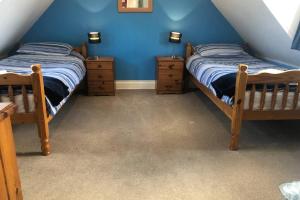 2 Einzelbetten in einem Zimmer mit blauen Wänden in der Unterkunft THE STUDIO ROUGHTON in Roughton