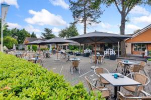 a patio with tables and chairs and umbrellas at Charmant chalet te Voorthuizen in Voorthuizen
