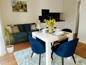 Apartamenty RÓŻANA 2 في ناووتشوف: غرفة معيشة مع طاولة بيضاء وكراسي زرقاء