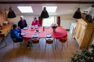 um grupo de pessoas sentadas à volta de uma mesa vermelha em Hageland Vakantieverblijf em Holsbeek