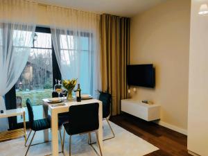 a living room with a table with chairs and a television at Apartamenty RÓŻANA 2 in Nałęczów