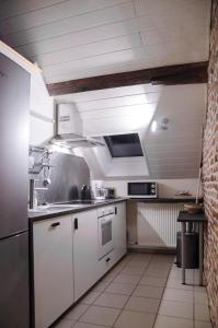 a kitchen with white cabinets and a stove top oven at Hageland Vakantieverblijf in Holsbeek