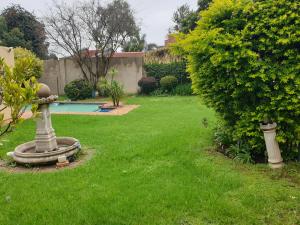 a yard with a garden with a bird bath in the grass at Matina Guest House in Johannesburg